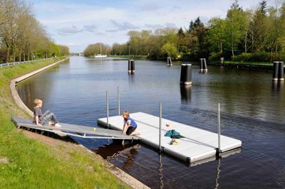 Barn sitter på en landgång vid en EasyFloat brygga i en kanal med lugnt vatten 