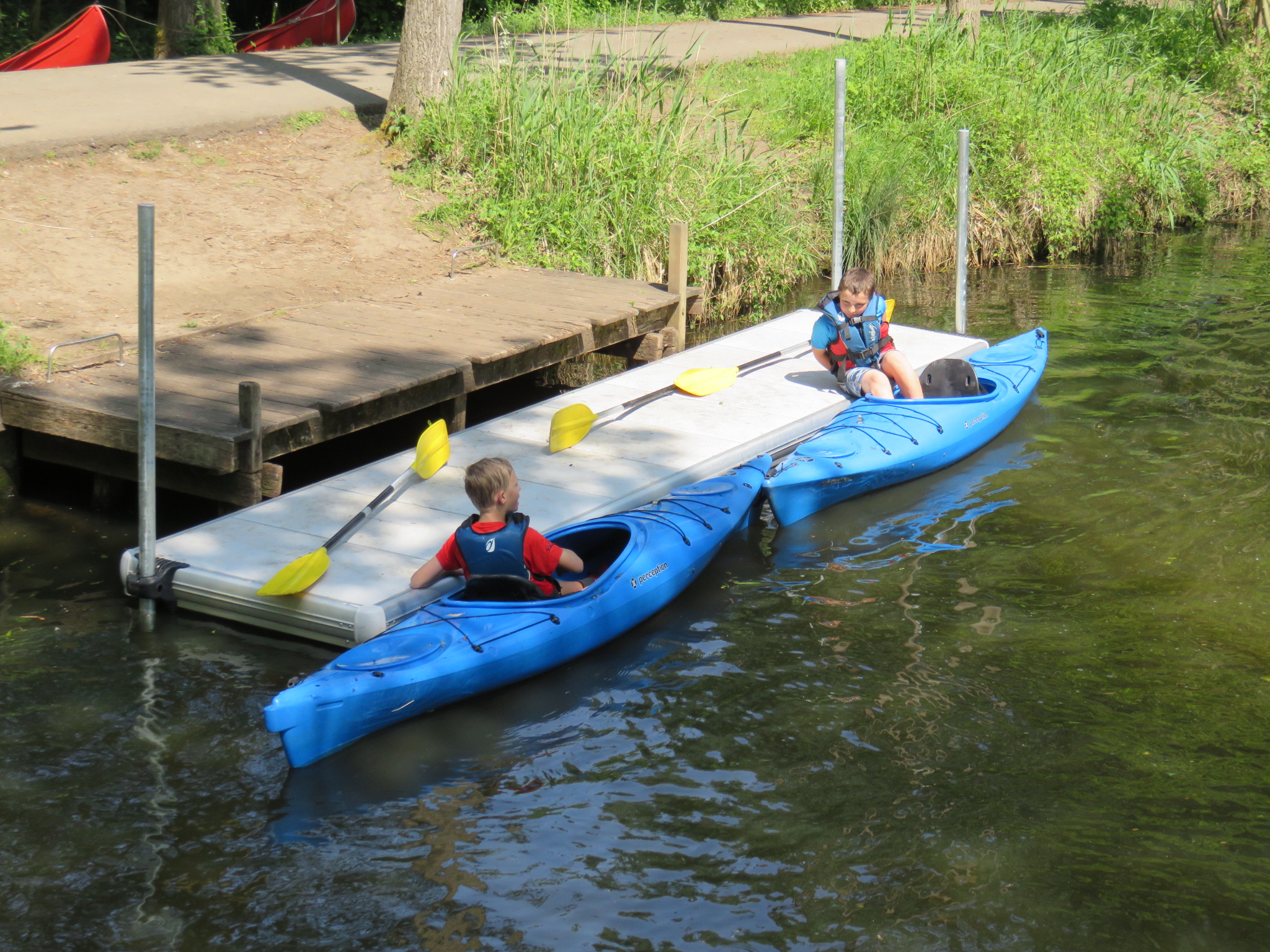 Barn sitter på en EasyFloat brygga och i kajak med åror, med enkel tillgång till vattnet i Puyenbroeck
