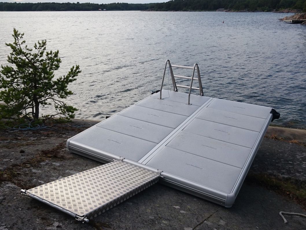 EasyFloat badflotte med landgång och badstege uppdragen på land vid vattnet, redo för användning.