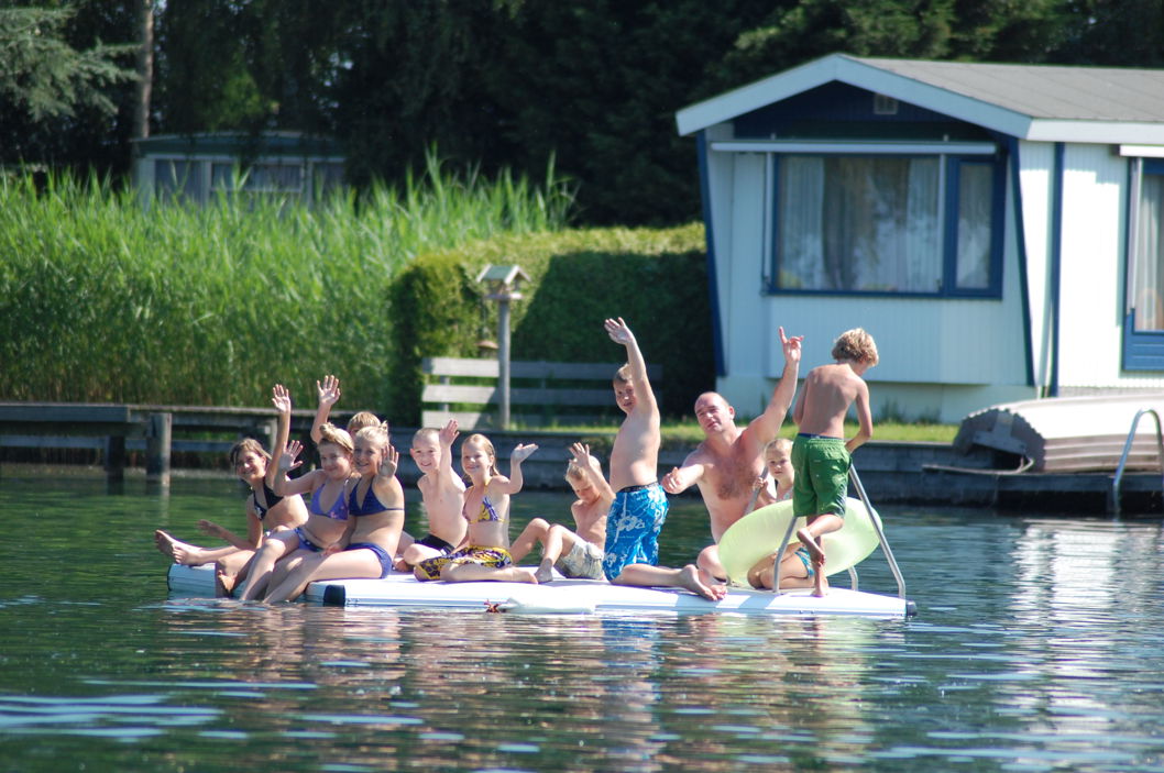 Personer som njuter av en EasyFloat badflotte på en sjö i Holland och vinkar från flotten