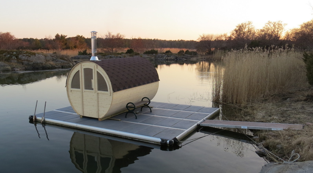 EasyFloat bastuflotte med Alfreds Runda bastun ovanpå, sittbänk och landgång på vattnet i höst- eller vårmiljö.