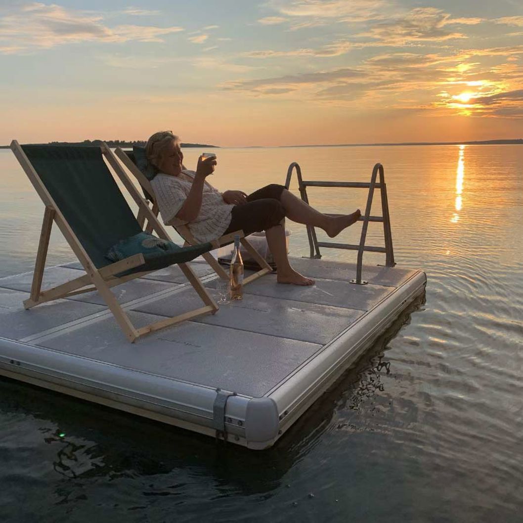 EasyFloat-flotte med badstege och solstolar, placerad på en sjö i solnedgången